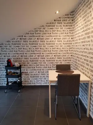 a table with two chairs and a wall with writing on it at B&B De Vlierbeek in Sint-Niklaas