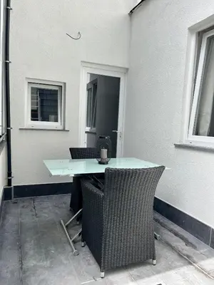 a table and chairs on a patio with two windows at Stilias Apartment 4P Brussels City in Brussels