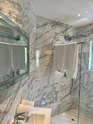 a bathroom with a marble wall with a sink and a shower at Stilias Apartment 4P Brussels City in Brussels