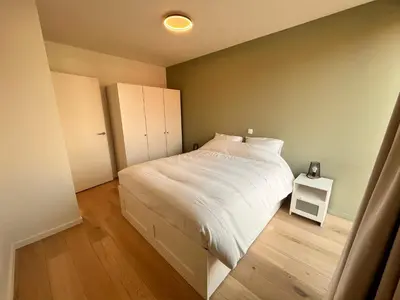 a bedroom with a white bed and a white night stand at Casa Matti - Modern Apartment with Garden View and Terrace in Ghent