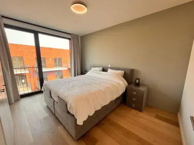 a bedroom with a bed and a large window at Casa Matti - Modern Apartment with Garden View and Terrace in Ghent