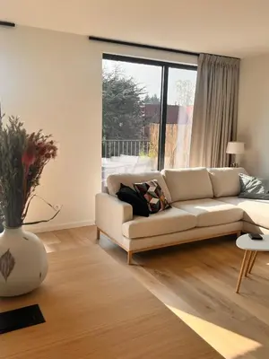 a living room with a white couch and a large window at Casa Matti - Modern Apartment with Garden View and Terrace in Ghent