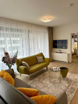 a living room with a green couch and a television at Urbanstay Suites - Jacqmain Downtown Suite in Brussels