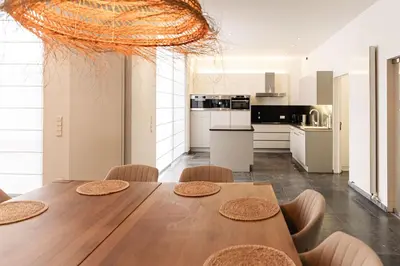 a kitchen and dining room with a wooden table and chairs at Casa Tintos in Sint-Amands