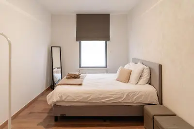 a bedroom with a bed with white sheets and a window at Casa Tintos in Sint-Amands