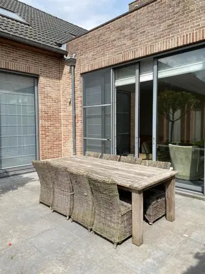 a wooden table and chairs in front of a brick building at Casa Tintos in Sint-Amands