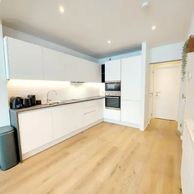 a kitchen with white cabinets and a wooden floor at New Luxe Grand place Apartment in Brussels