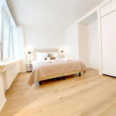a white bedroom with a bed and a wooden floor at New Luxe Grand place Apartment in Brussels