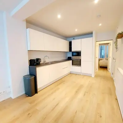 a kitchen with white cabinets and a hardwood floor at New Luxe Grand place Apartment in Brussels