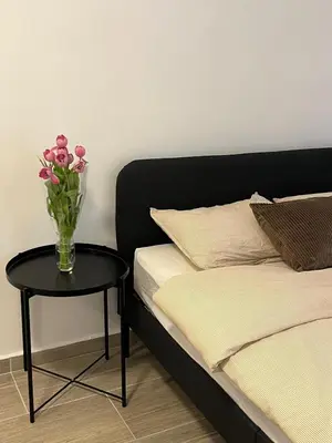 a vase of pink flowers on a table next to a bed at Rue blaes Appartement in Brussels