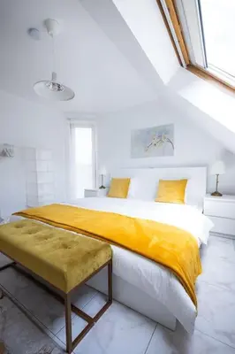 a bedroom with a large bed with a yellow blanket at Résidence Orchidée in Zaventem