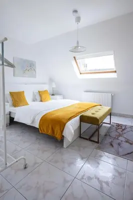 a white bedroom with a bed with a yellow blanket at Résidence Orchidée in Zaventem