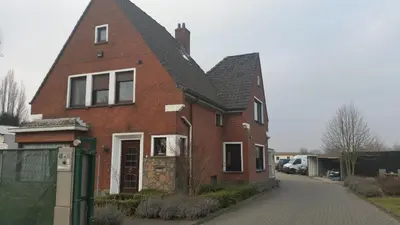 a red brick house on a street with a driveway at Guest House Scheldevallei in Merelbeke
