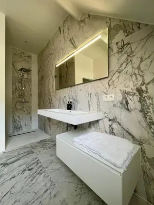 a bathroom with a white sink and a marble wall at Stilias Apartment 6P City Center in Brussels