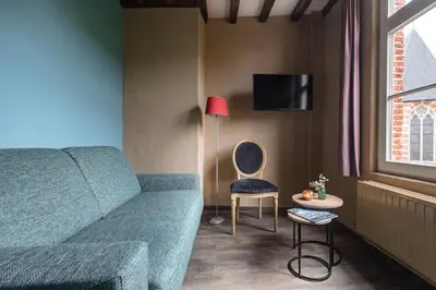 a living room with a couch and a table and a lamp at B&B CONVENT Begijnhof Herentals in Herentals