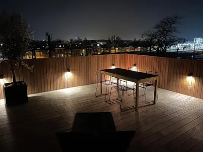 a table and chairs on a deck at night at Penthouse with Airconditioning and Big Terrace, Close to Gent Sint-Pieters Station and City Centre in Ghent
