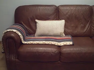 a brown leather couch with a pillow on it at Apartment Capitalcondos in Ninove