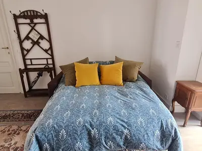 a bed with blue and yellow pillows in a room at Appartement Voltaire in Brussels