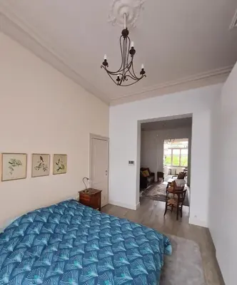 a bedroom with a blue bed and a chandelier at Appartement Voltaire in Brussels