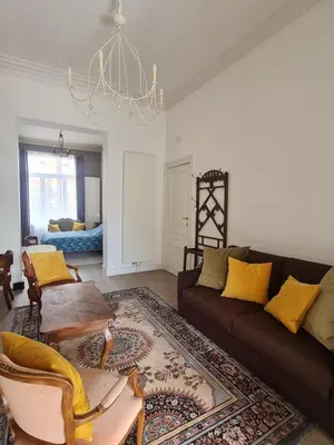 a living room with a brown couch and yellow pillows at Appartement Voltaire in Brussels