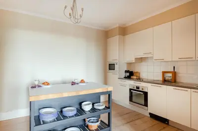 a kitchen with white cabinets and a shelf with dishes at Brussels EU Prestige residence in Brussels