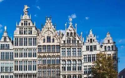 a tall white building with a statue on top of it at FLAX ANTWERP in Antwerp