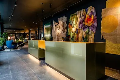 a lobby with a counter with art on the wall at Motel One Antwerp in Antwerp