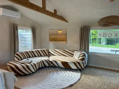 a living room with a couch and a large window at Chalet Leon in Geel