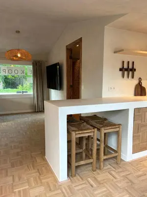 a kitchen with a counter with stools and a tv at Chalet Leon in Geel