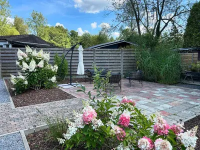 a patio with flowers and an umbrella and a fence at Chalet Leon in Geel