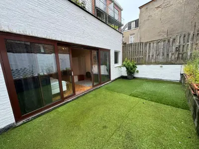 a backyard with a green lawn next to a building at Garden loft in city center Meir 1FL in Antwerp