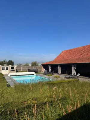 a swimming pool in front of a house at B&B De Vreehoeve in Merksplas