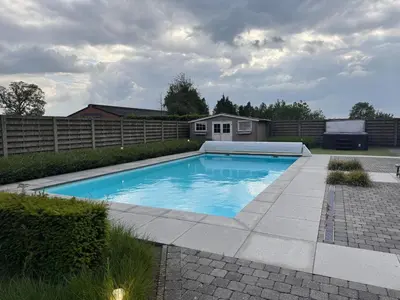 a swimming pool in a yard with a fence at B&B De Vreehoeve in Merksplas