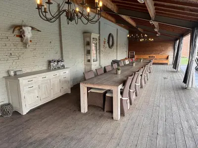 a dining room with a long wooden table and chairs at B&B De Vreehoeve in Merksplas