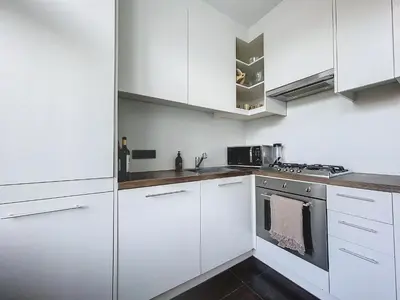 a white kitchen with white cabinets and a stove at Churchill - Brugmann square in Brussels