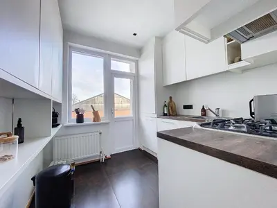 a kitchen with white cabinets and a large window at Churchill - Brugmann square in Brussels