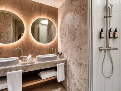 a bathroom with two sinks and a shower at Mövenpick Hotel Brussels Airport in Zaventem
