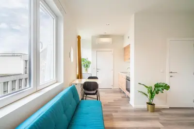 a living room with a blue couch and a kitchen at Cozy Antwerp City Apartments in Antwerp