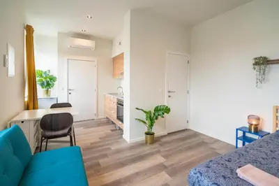 a living room with a blue couch and a kitchen at Cozy Antwerp City Apartments in Antwerp
