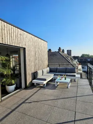 a patio with a couch and a table on a roof at Penthouse with big terrace in Vilvoorde