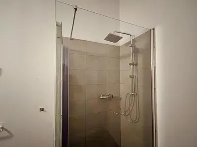 a shower with a glass door in a bathroom at European District Hostel in Brussels