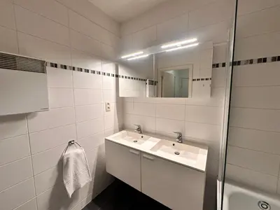 a white bathroom with a sink and a mirror at Cosy 2 Bedroom Apartment in City Center in Brussels