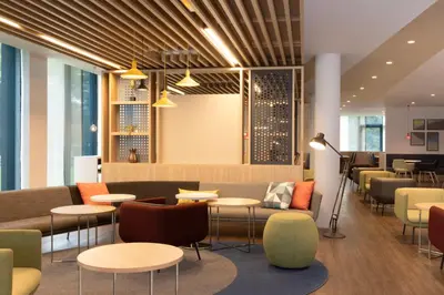 a restaurant with tables and chairs and a lobby at Holiday Inn Express Brussels - Airport by IHG in Diegem