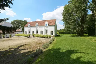 a white house with a red roof on a yard at Le cottage de la Verte Voie in Wavre