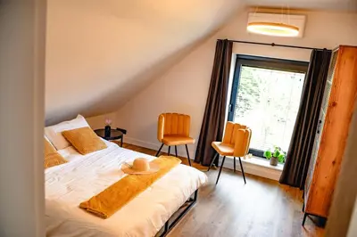 a bedroom with a bed with two chairs and a window at De Krekelberg in Brecht