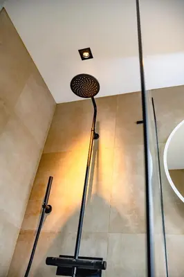 a floor lamp in a room with a shower at De Krekelberg in Brecht
