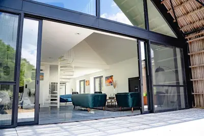 a glass extension of a house with two green chairs at De Krekelberg in Brecht