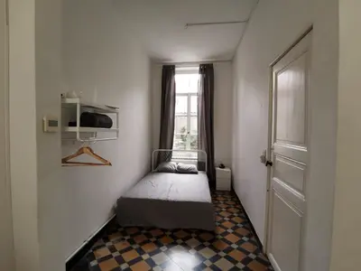 a small bedroom with a bed and a window at Spacious room in city centre in Ghent