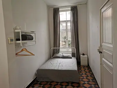 a small bedroom with a bed and a window at Spacious room in city centre in Ghent
