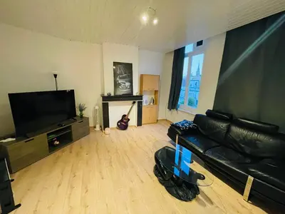 a living room with a black leather couch and a flat screen tv at Heart of Antwerp in Antwerp